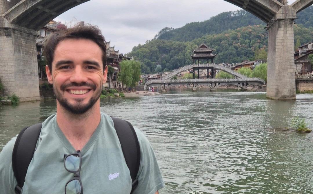Luis Eduardo de Miguel junto a un río, con un puente histórico al fondo